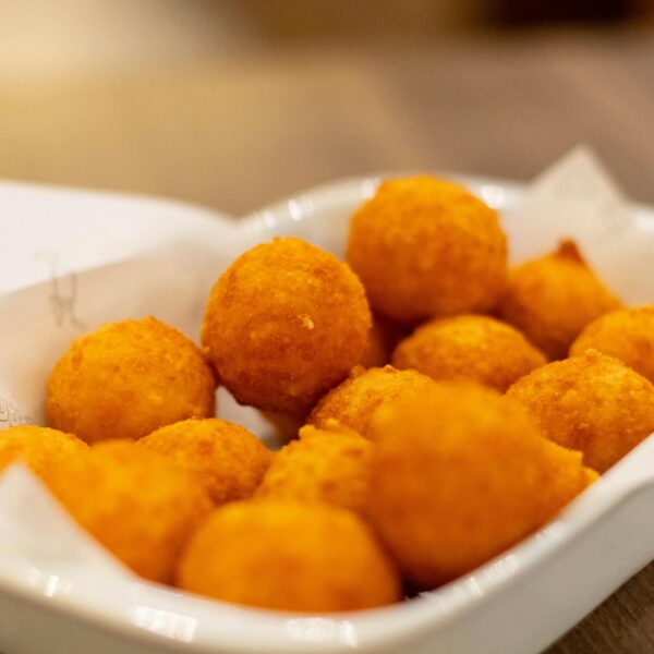 Appetizing golden cheese balls served on a white platter, perfect for snacking.